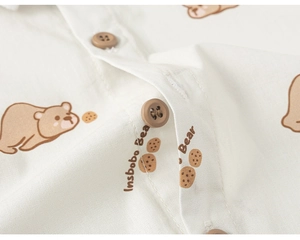 Close-up of cotton baby shirt fabric with cartoon bear prints and dark brown buttons