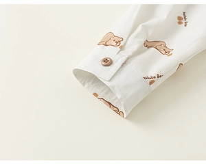 Detail of white shirt cuff featuring brown cartoon bear prints and resin button closure