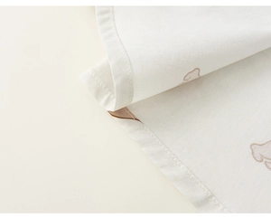 Detail of baby cotton linen shirt hem with soft cartoon prints and neat stitching