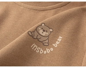 Close-up of brown knit sweater with a cute cartoon bear and insbobo bear print detail
