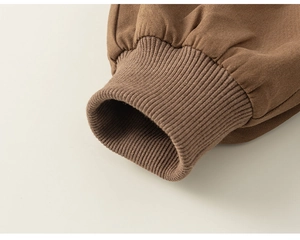 Close-up of brown woven fabric showing ribbed knit cuff detail and fine twill texture