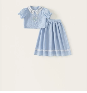 Detail of blue girl's shirt with lace collar and embroidery paired with a matching skirt