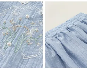 Detail of floral butterfly embroidery, pearl buttons, and elastic waistband on light blue set