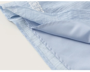 Detail of light blue skirt hem with delicate white floral embroidery and silky lining