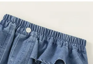 Close-up of girls denim skort featuring elastic waist with button and ruffle hem detail