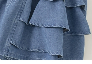 Close-up of layered ruffle design and textured blue denim fabric on girl's skirt shorts