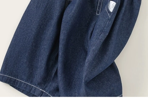 Detail view of dark blue denim fabric with white contrast stitching and product label