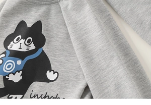 Detail of grey kid's sweatshirt showing soft fabric texture and cartoon cat print