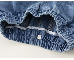 Close-up of girls denim skirt shorts featuring elastic waistband and silver metal button