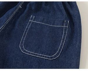 Detailed close-up of dark blue denim fabric with white contrast stitching on pocket
