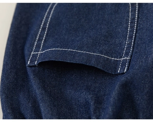 Detail of dark blue denim shorts showing white contrast stitching and pocket texture