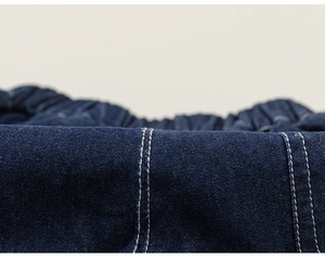 Detailed macro view of dark blue denim shorts featuring elastic waist and white contrast stitching
