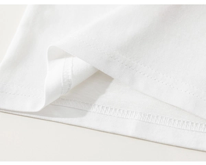 Detail of the high-density double-stitch hem on the white cotton t-shirt fabric