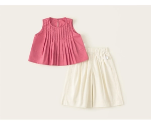 Dettaglio del top a pieghe rosa senza maniche e pantaloni larghi beige in cotone