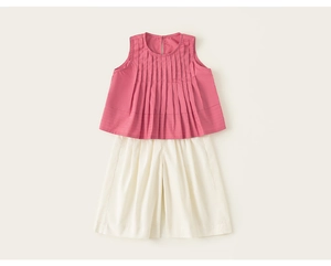 Dettaglio completo estivo da bambina con top rosa a pieghe e pantaloncini beige