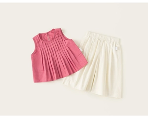 Dettaglio del top rosa senza maniche a pieghe e dei pantaloncini bianchi per bambina