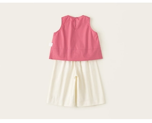 Dettaglio top senza maniche rosa con bottone sulla schiena e pantaloni ampi crema