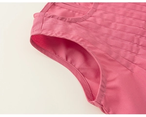 Dettaglio ravvicinato del tessuto plissettato rosa e cuciture rifinite sul completo estivo