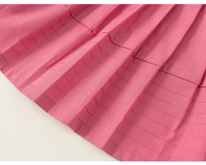 Dettaglio del tessuto plissettato rosa con cuciture decorative bianche su top estivo