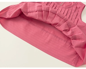 Dettaglio del top senza maniche a pieghe rosa con cuciture rifinite e trama del tessuto
