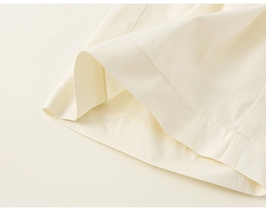 Dettaglio delle cuciture e dell'orlo sui pantaloni in cotone bianco sporco per bambina