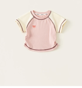Close-up of pink raglan sleeve t-shirt with orange bow print and contrast trim