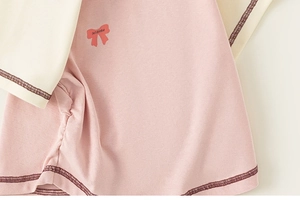 Detail of baby girl raglan tee featuring pink bow print and contrast stitching accents