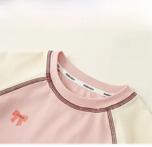 Detail of girls' raglan tee showing pink bow print and ribbed round neckline stitching