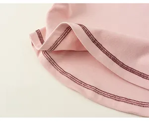 Close-up of pink ribbed fabric hem with red double-stitching and neat finish