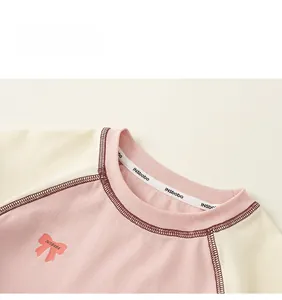Close-up of pink raglan sleeve collar with bow print and internal branded tape detail