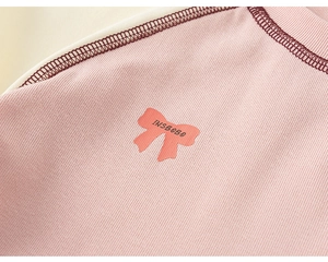 Macro detail of the pink ribbed cotton fabric with bow print and decorative stitching