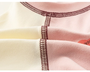 Detail view of cotton t-shirt neckline with contrast stitching and heart-shaped logo