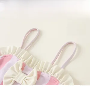 Détail d'un maillot de bain rayé rose et blanc avec noeud crème et volants