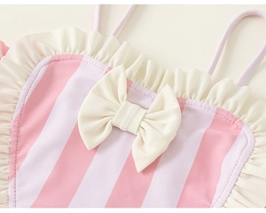 Détail de maillot de bain fille à rayures roses et blanches avec volants et un nœud mignon