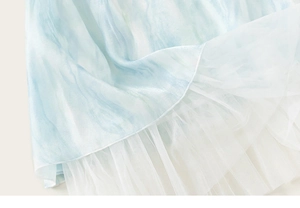Détail du tissu en soie à motifs d'encre bleue et tulle en maille blanche de la robe