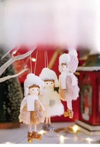 Detailed view of three plush angel doll ornaments with knit hats on white branches