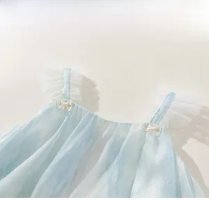 Détail d'une robe en tulle bleu pour fille avec nœuds et perles sur les bretelles