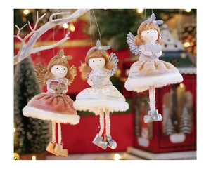 Three plush Christmas angel ornaments with glitter wings and velvet skirts on holiday background
