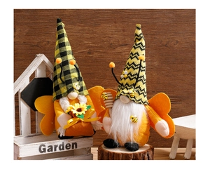 Close-up of handmade bee gnomes with striped hats holding a sunflower and honey wand