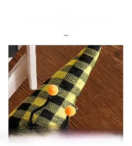 Detail of checkered gnome hat with orange pom-poms and yellow-black knit texture