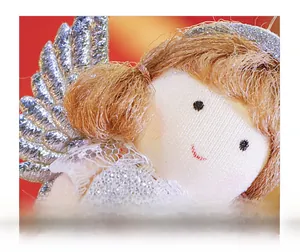 Close-up detail of angel girl doll face with knit fabric, embroidery and silver wings