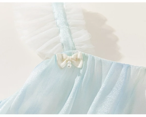 Détail de robe bleue pour fille avec bretelles volantées blanches, nœud perlé et tissu brillant