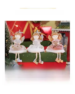 Three angel girl figurines with sequin wings sitting on a festive green gift box