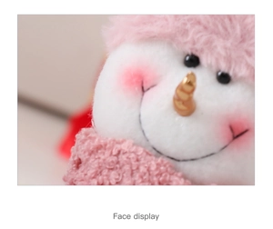 Vista dettagliata del viso di un pupazzo di neve in peluche con naso d'oro e cappello rosa