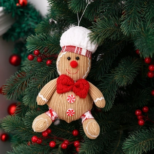 Gingerbread man plush ornament with chef hat and red bow on a decorated Christmas tree