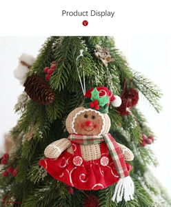 Detail of knitted gingerbread girl ornament with sequin dress hanging on a Christmas tree
