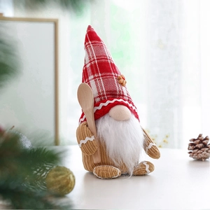 Detail of Christmas gnome with red plaid hat and wooden spoon among festive pine branches