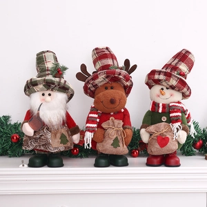 Drei Weihnachts-Plüschfiguren: Weihnachtsmann, Elch und Schneemann auf Kamingesims