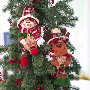 Christmas snowman and reindeer plush ornaments with plaid hats hanging on a festive tree