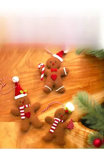 Three gingerbread man felt ornaments with festive candy canes and scarf on wood background